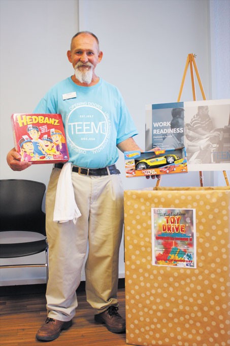 Tony Williamson, a former TEEM participant and now employee, holds two holiday gifts donated to be distributed to Oklahoma children who have a parent in prison this holiday season. | Photo Laura Eastes